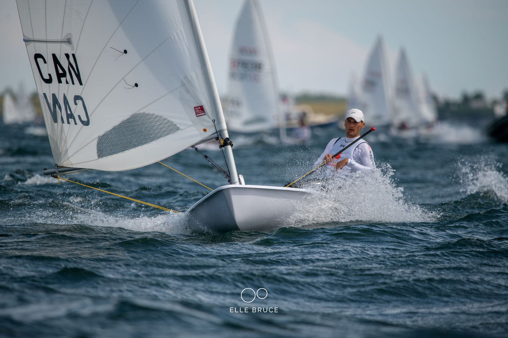 ILCA 7 fleet racing with Canadian sails and mountain backdrop