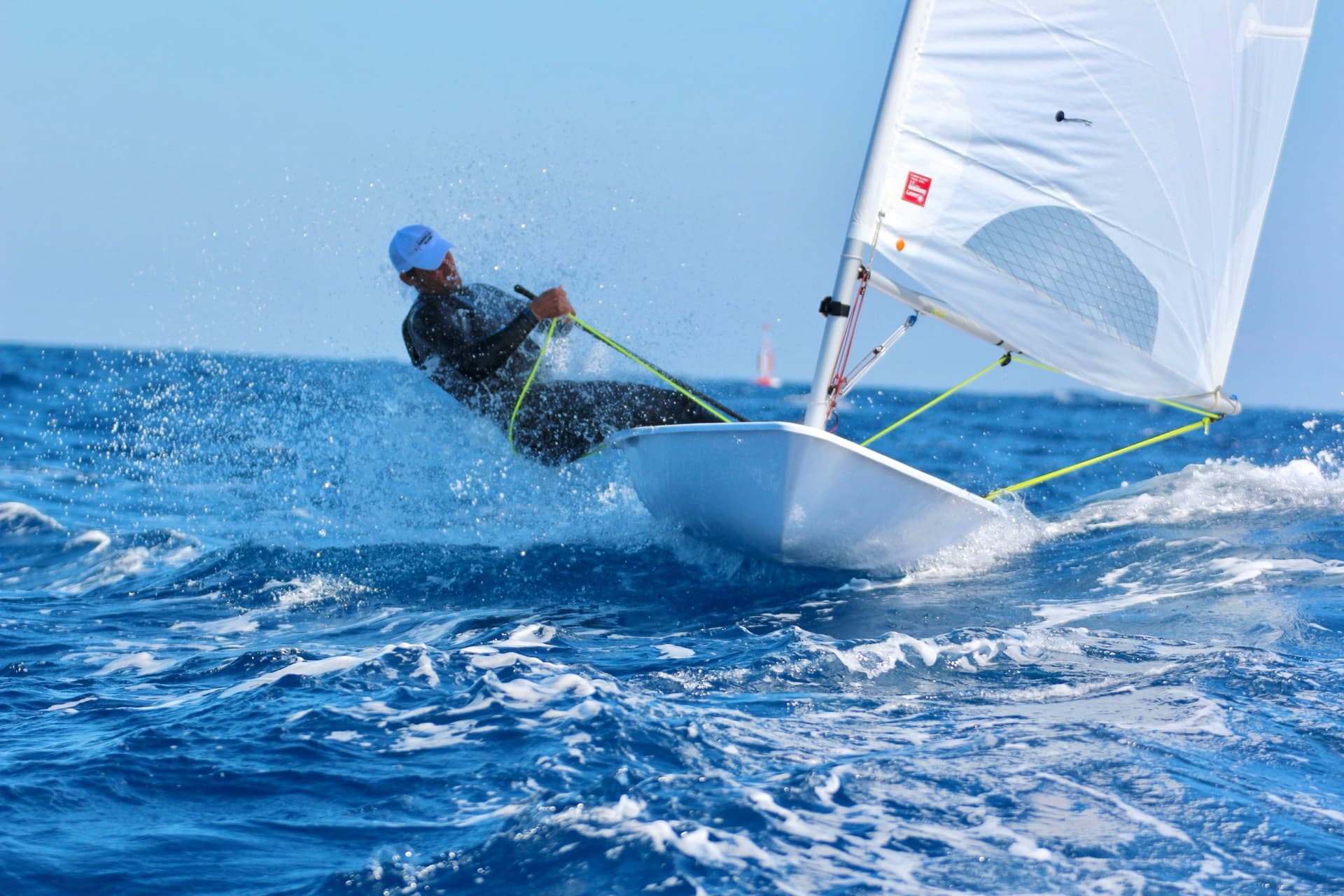 James racing in Europe with CAN on the sail and Mediterranean coastline behind